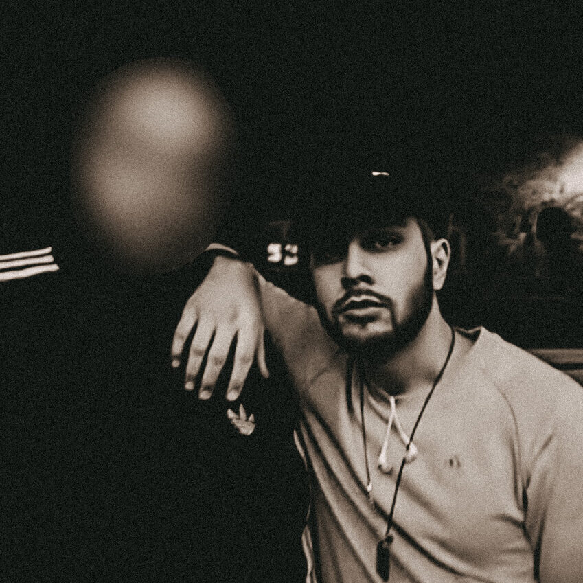 Isa Ulubaev schaut gelangweilt mit dem Arm auf der Schulter eines unkenntlich gemachten Mannes in Richtung Kamera