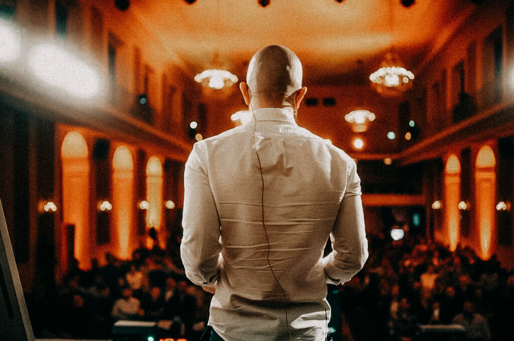 Isa Ulubaev von Hinten zu sehen, wie er auf der Bühne in Richtung Publikum schaut